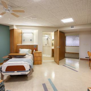 A modern hospital room with a single bed and attached bathroom.