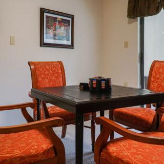 A cozy dining room setup with four orange-upholstered chairs around a square table.