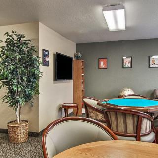 A cozy lounge area featuring a round table with chairs, a potted plant, a wall-mounted television, and decorative framed art.