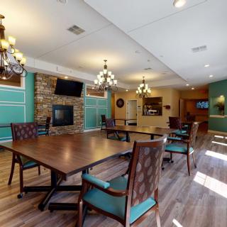 A well-decorated dining room with wooden tables, upholstered chairs, chandeliers, and a cozy fireplace.