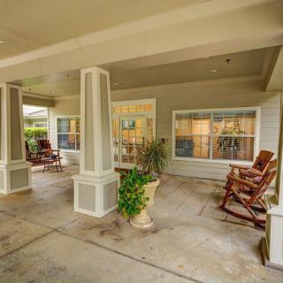A welcoming covered patio with rocking chairs and decorative plants.