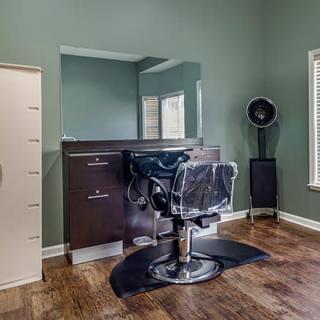 A stylish barbershop setup featuring a classic barber chair, large mirror, and hair dryer in a modern interior.