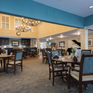 A cozy dining area with elegant furniture, a chandelier, and a grand piano.