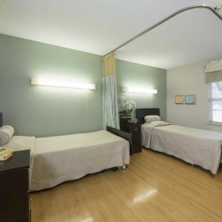 A clean, minimalistic hospital room with two patient beds separated by a curtain divider.