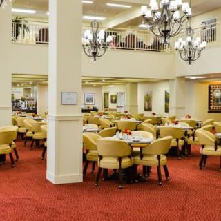 A spacious and elegant dining area with multiple tables and chairs, adorned with chandeliers.