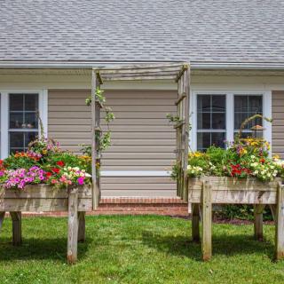 A charming garden setup with flower-filled planters and a decorative trellis in front of a house.