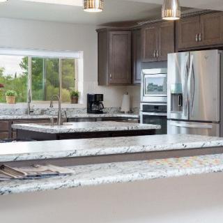Modern kitchen with stainless steel appliances and marble countertops.