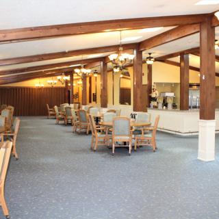 A spacious dining area with wooden beams and neatly arranged tables and chairs.