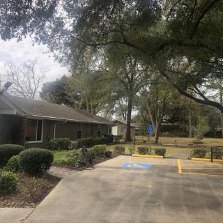 A small building surrounded by trees with an adjacent parking lot.