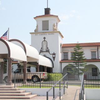 A historical building with a tower and arches, featuring an American flag and an outdoor entrance area.