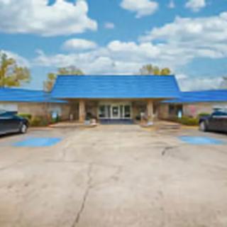 A small motel with a distinctive blue roof and parking area.