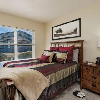 A cozy bedroom with a neatly made bed, bedside table, and large window.