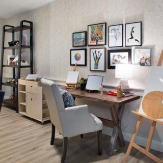 A cozy and stylish home office with a wooden desk, comfortable chair, and framed artwork on the wall.