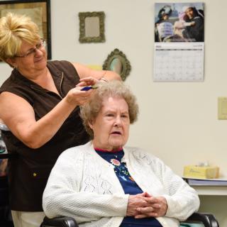 A hairdresser styles the hair of an elderly woman in a beauty salon.