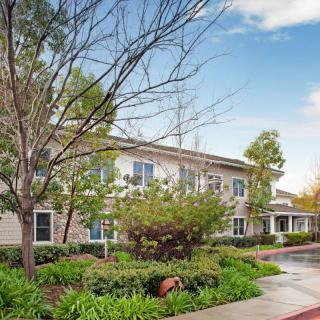 A well-landscaped residential building surrounded by trees with a clear sky in the background.