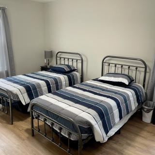 A minimalist bedroom with twin metal-framed beds featuring striped bedding and wooden floors.
