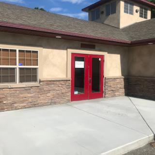 A view of a building's entrance showcasing red double doors and a stone facade.