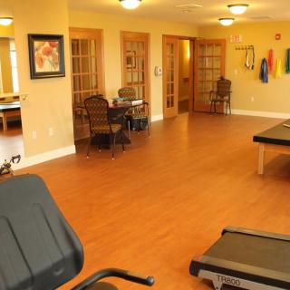 A well-lit fitness room featuring exercise equipment and wooden flooring.