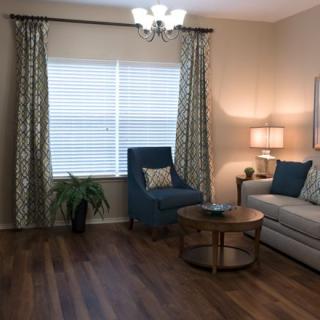 A cozy living room with a sofa, armchair, and coffee table, featuring elegant curtains and soft lighting.