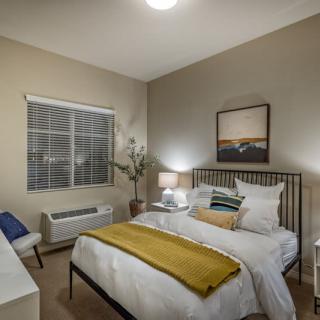 A modern bedroom interior with a neatly made bed, soft lighting, and wall art.