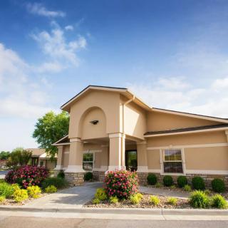 A well-maintained building surrounded by landscaped gardens under a clear blue sky.