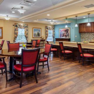 A modern dining area with wooden flooring, red cushioned chairs, and stylish lighting fixtures.
