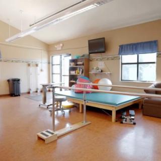 A bright and spacious rehabilitation room equipped with exercise and therapy equipment.