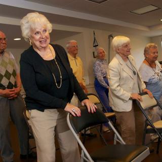 A group of seniors participating in a chair exercise class indoors.