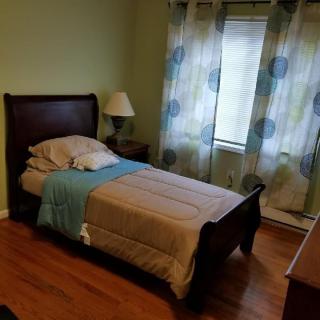 A cozy bedroom with a single bed, lamp, and patterned curtains.