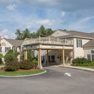 A scenic view of a residential building entrance with landscaped surroundings.
