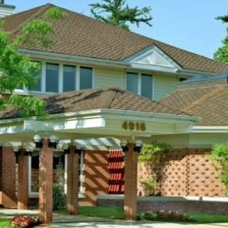 A beautiful residential home showcasing a well-designed front porch and lush greenery.