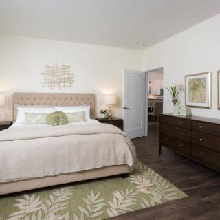 A cozy bedroom with neutral tones, featuring a large bed, stylish decor, and a patterned rug.