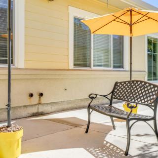 A sunny patio with a metal chair and a yellow umbrella.