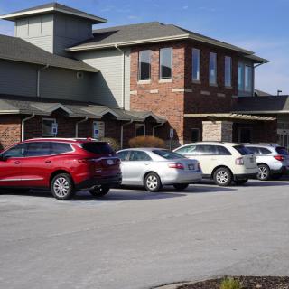A suburban building with multiple cars parked in the parking lot.