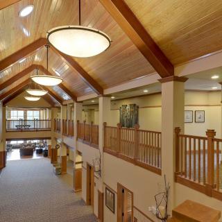 A spacious hallway with wooden ceilings and elegant lighting, featuring a balcony overlooking the area.