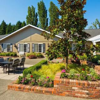 A charming house with well-maintained landscaping, featuring a garden, brick planter, and outdoor seating area.