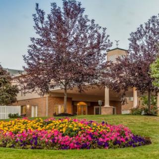 A beautifully landscaped garden with colorful flowers and trees in front of a building.