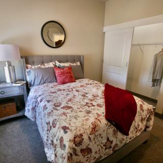 A cozy bedroom with floral bedding, a mirror, and an open closet.