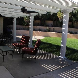 A backyard patio with a pergola providing shade for outdoor furniture.