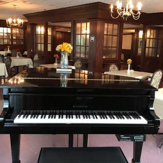 A beautifully arranged black grand piano in an elegant restaurant setting.