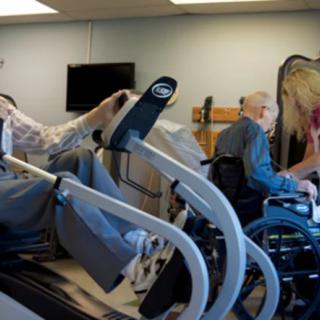 Elderly individuals engaging in physical therapy exercises using specialized equipment in a healthcare facility.