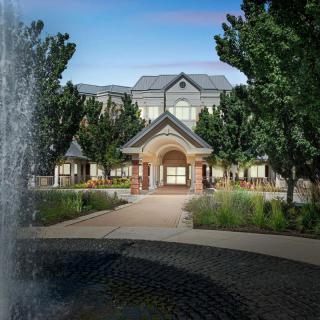 A scenic view of a building with a fountain and lush greenery.