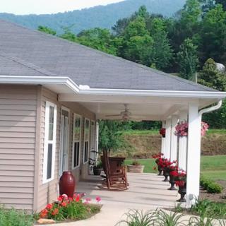 A charming house with a porch, set against a scenic mountain backdrop.