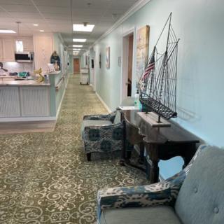 A hallway with a comfortable waiting area featuring chairs, a model ship, and decorative elements.