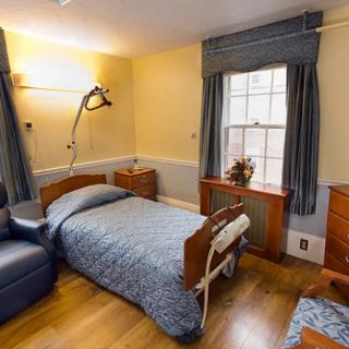 A hospital room with a patient bed, chair, and window with curtains.