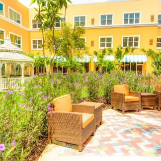 A sunny outdoor garden patio with comfortable seating and a view of the building.