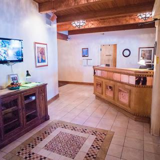 A cozy lobby area featuring a wooden reception desk, wall-mounted TV, and decorative artwork.