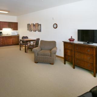 A cozy living space with a television, comfortable armchair, and dining area near the kitchen.