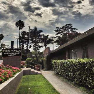 A scenic view of an apartment building with a cloudy sky and lush greenery.