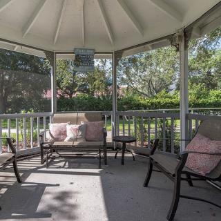 A cozy gazebo with comfortable patio furniture, perfect for relaxing in a garden setting.